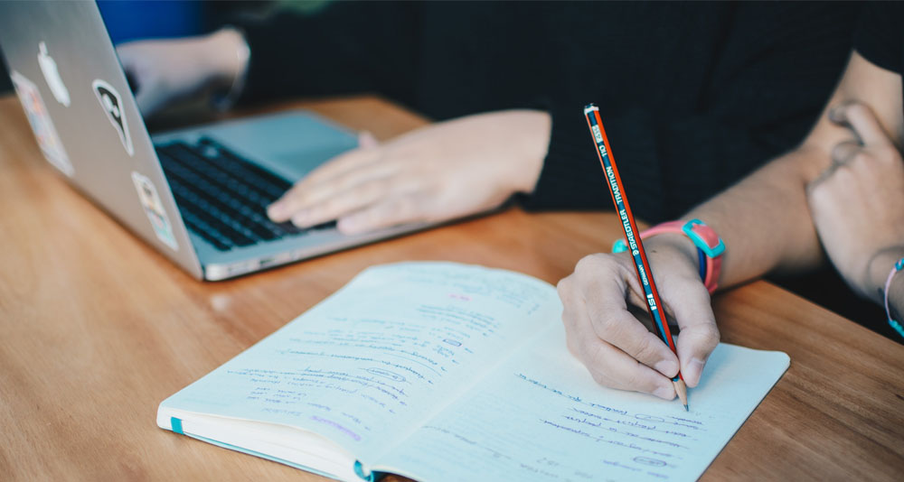 Person on laptop while another person takes notes
